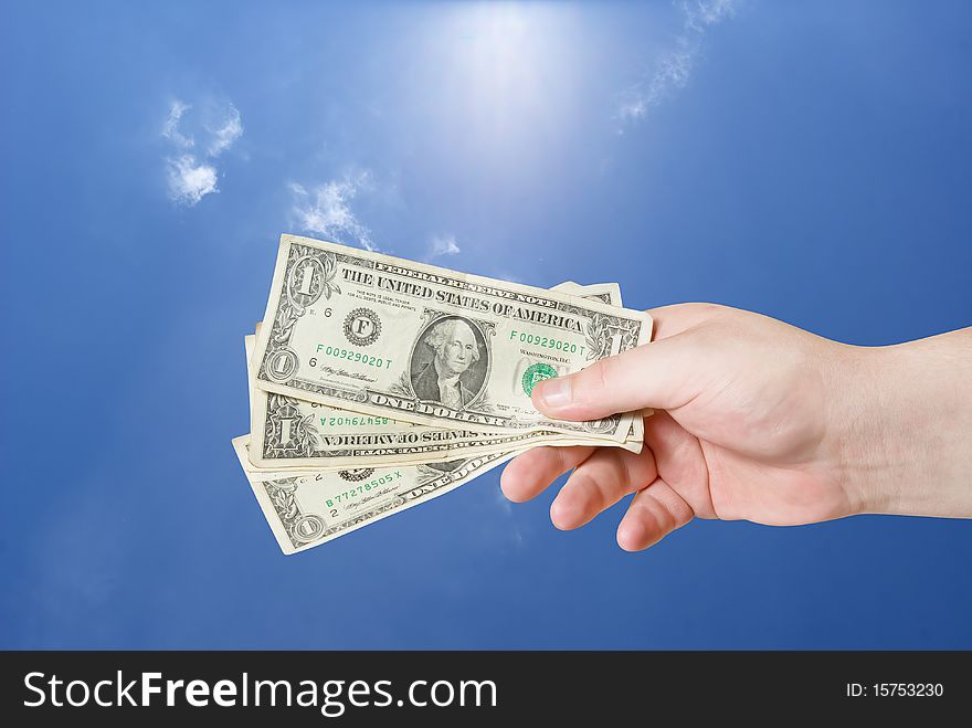 American dollar in hand on blue sky background