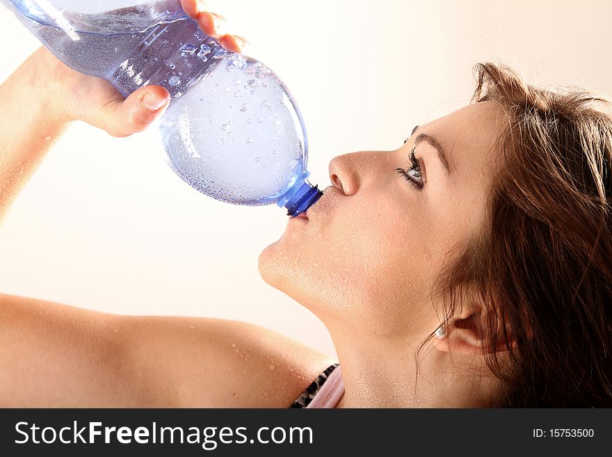 Young woman drinking water out of the bottle after training. Young woman drinking water out of the bottle after training