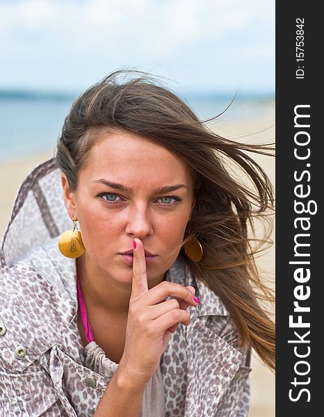 Young attractive woman with his finger around his lips. Portrait of a Woman. Outdoor, summer.