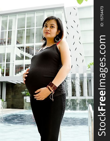 Portrait of healthy Asian ethnic pregnant woman standing by the pool. Portrait of healthy Asian ethnic pregnant woman standing by the pool
