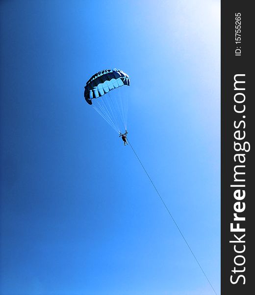 Parachuter descending with a parachute with cable and boat