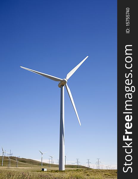 The white wind turbine generating electricity on blue sky. The white wind turbine generating electricity on blue sky