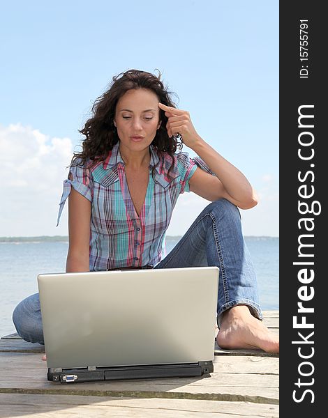 Woman using laptop computer on a pontoon. Woman using laptop computer on a pontoon