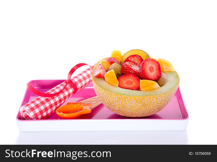 A melon filled with juicy colorful fruits on a pink plate isolated over white. A melon filled with juicy colorful fruits on a pink plate isolated over white