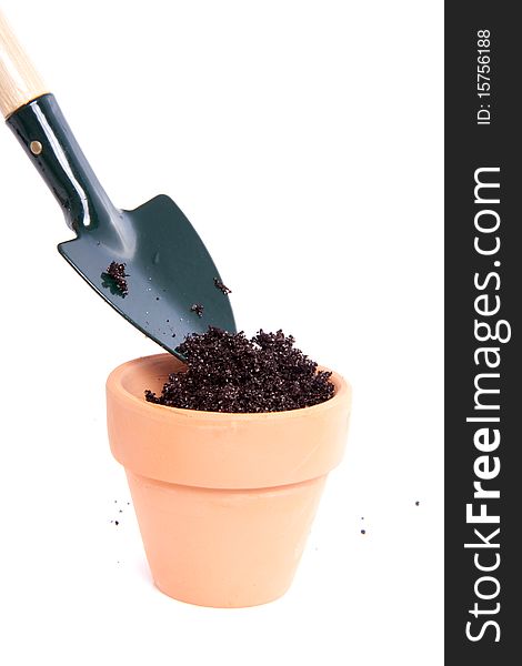 Putting soil in a terracotta pot with a garden shovel isolated over white. Putting soil in a terracotta pot with a garden shovel isolated over white