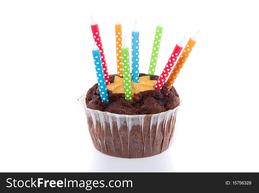 Birthday candles on top of a chocolate muffin isolated over white. Birthday candles on top of a chocolate muffin isolated over white