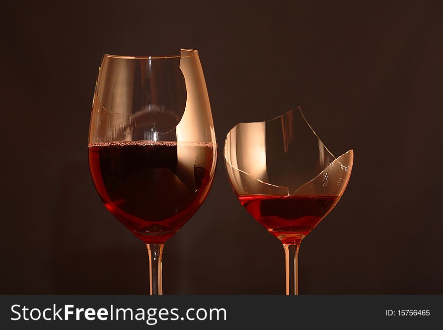Two broken goblets with red wine on dark background. Two broken goblets with red wine on dark background