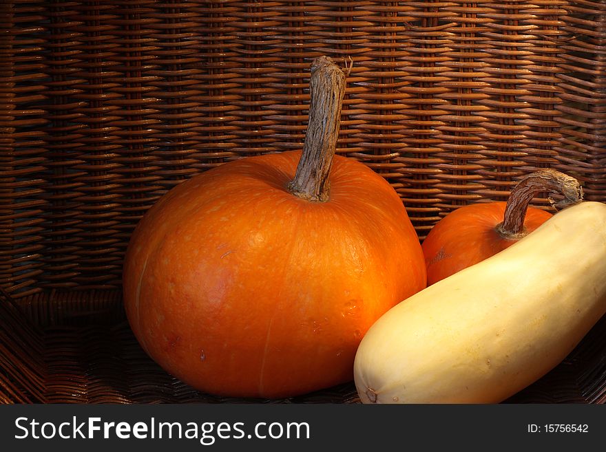 Two pumpkins and marrow squash inside wicker basket. Two pumpkins and marrow squash inside wicker basket