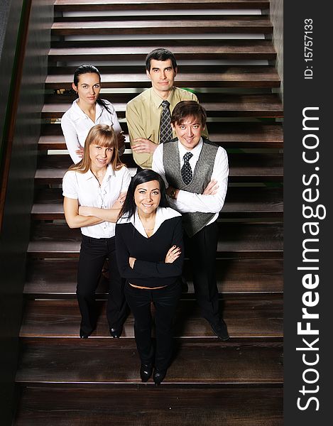 Five young business persons are standing as a team with a man in front. The image is taken on the stairs. Five young business persons are standing as a team with a man in front. The image is taken on the stairs.