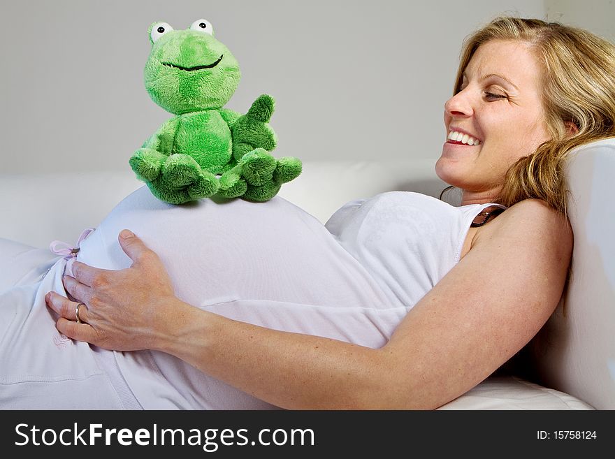 Young fresh pregnant woman with baby toys. Isolated over white background. Young fresh pregnant woman with baby toys. Isolated over white background.