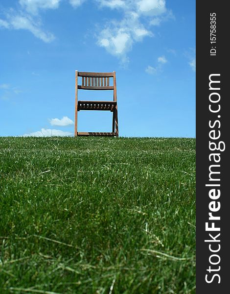 A Wooden chair with grass and sky. A Wooden chair with grass and sky