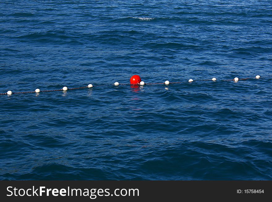 Red buoy in a rope in the blue sea. Red buoy in a rope in the blue sea