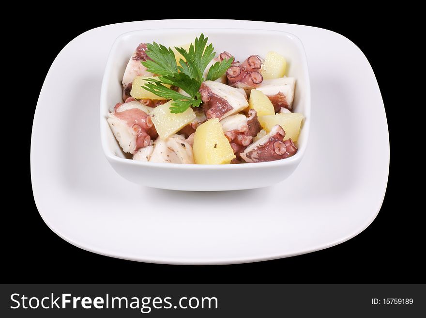 Octopus with potatoes served in a white dish. Isolated on black with clipping path