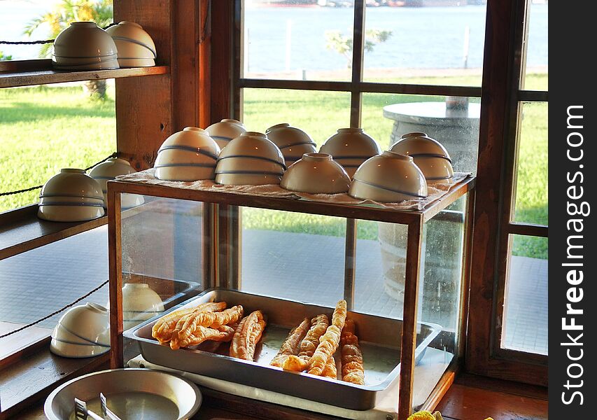 A stall sells Chinese fried breadsticks and bowls of soybean milk. A stall sells Chinese fried breadsticks and bowls of soybean milk