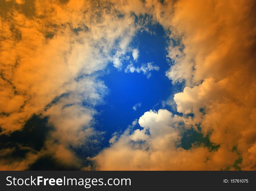 Wide angle view of puffy clouds in blue sky overlaid with orange. Wide angle view of puffy clouds in blue sky overlaid with orange