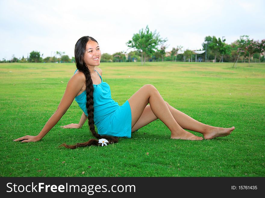 Young woman with long hair sitting on green grass in the park. Young woman with long hair sitting on green grass in the park