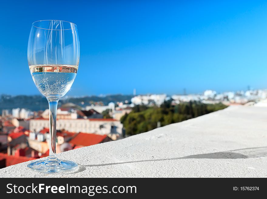 Glass Of White Wine Against The Roofs And Blue Sky