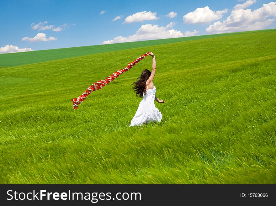 Summer girl with colorful scarf running through green field