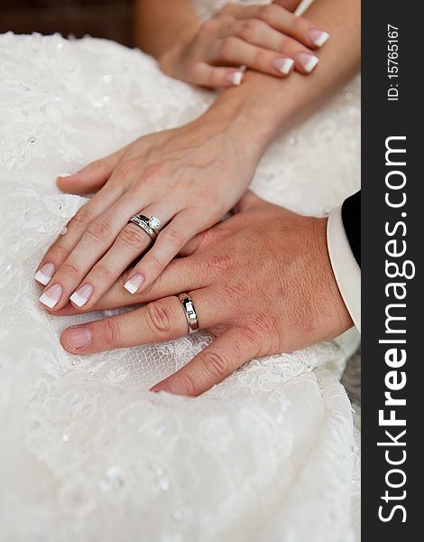 Gently connected hands of a newly-married couple with wedding rings