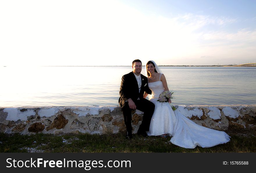 Wedding Couple Sitting By Water