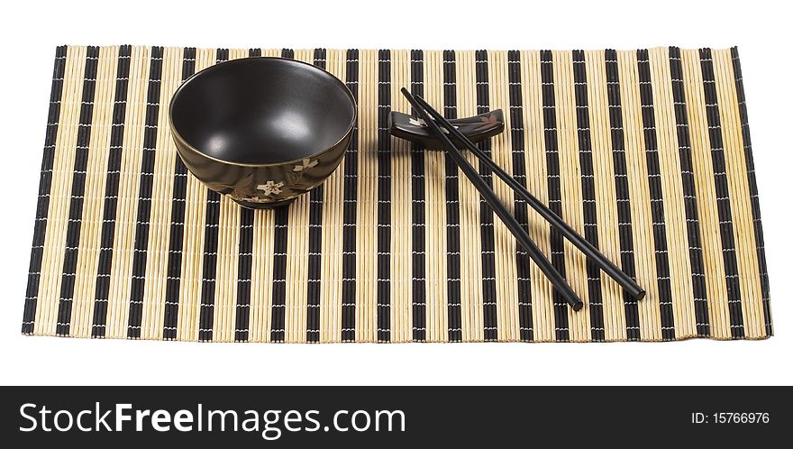 Wooden chopsticks and little ceramic bowl on the bamboo mat isolated over white background. Wooden chopsticks and little ceramic bowl on the bamboo mat isolated over white background