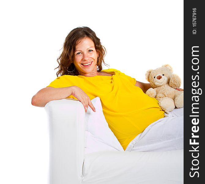 Young expecting mother is sitting on a couch at home. Highkey image over pure white background.