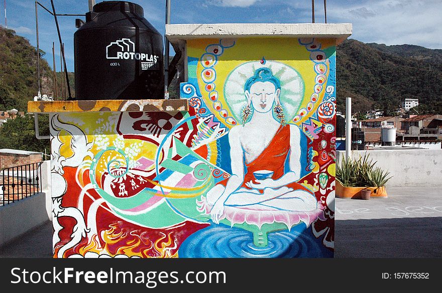 Mural of Vajrasattva - Dorje Sempa - with Mexican Iconography Fly me round trip from Seattle to anywhere &#x28;especially Puerto Vallarta&#x29; to paint more murals. A mural mixing Mexican and Tibetan Buddhist iconography on a rooftop in Puerto Vallarta, Mexico, completed Jan 1, 2007. As a mixed image this is not, strictly speaking, an image of Vajrasattva, but Tibetan iconography with Mexican and international iconography in my own style. This is a buddha of purity and purification, part of the basic practices. It was painted as a present for the friends I stayed with there - Rossy and Ariel. It&#x27;s approximately 7 ft by 7 ft square. It was painted on reinforced concrete. It is on the back of the enclosed staircase. Took a little over 3 days to paint - totally on the fly - no preliminary drawings - I just started painting. To the right of the skulls you will see a skeleton of my friend&#x27;s dog, Breda. The colorful red section above is influenced by the local Huichol art. Ariel is a homegrown biologist - his company is &quot;Wild Travellers&quot; - he is an ethusiastic eco-tourguide, and conservationist of endangered species of turtles. He was voted the best tourguide by tourists in North Vallarta. This image stands in for a shrine. What I am trying to convey is that Buddhism can be a wholesome and creative influence on Mexican culture. &quot;Rotoplas&quot; on the black plastic container stands for the manufacturing technique - rotational plastic - it&#x27;s a water filter and storage device - a cistern. -------------------- Mural de Vajrasatva - Dorje Sempa - IconografÃ­a mexicana Vuele ida y vuelta me de Seattle a cualquier lugar &#x28;especialmente en Puerto Vallarta&#x29; para pintar murales mÃ¡s. Un mural y la mezcla mexicana iconografÃ­a budista tibetano en una azotea en Puerto Vallarta, Mexico, completada 1 de enero de 2007. Como una mezcla de imagen esto no es, estrictamente hablando, una imagen de Vajrasatva, pero tibetano iconografÃ­a mexicana e internacional con la iconografÃ­a en mi propio estilo. Se trata de un buda de la pureza y la purificaciÃ³n, la parte de las prÃ¡cticas bÃ¡sicas. Se pintÃ³ como un regalo para los amigos que me quedÃ© allÃ­ - Rossy y Ariel. Es de aproximadamente 7 pies por 7 pies cuadrados. Fue pintado en hormigÃ³n armado. Es en la parte posterior de la escalera cerrada. TomÃ³ un poco mÃ¡s de 3 dÃ­as a la pintura - totalmente en el momento - no hay dibujos preliminares - Acabo de empezar la pintura. A la derecha de los crÃ¡neos verÃ¡ un esqueleto de mi amigo el perro, Breda. La secciÃ³n anterior de color rojo se ve influida por el arte huichol. Ariel es un biÃ³logo de la casa - su empresa es &quot;Wild Viajeros&quot; - que se trate de una visita ethusiastic ecolÃ³gica y conservacionista de especies amenazadas de tortugas. Fue elegido como el mejor visita por los turistas en el norte de Vallarta. Esta imagen se encuentra en un santuario. Lo que estoy tratando de transmitir es que el budismo puede ser una sana y creativa influencia en la cultura mexicana. &quot;Rotoplas&quot; en el contenedor de plÃ¡stico negro representa la tÃ©cnica de fabricaciÃ³n - de rotaciÃ³n de plÃ¡stico - es un filtro de agua y dispositivo de almacenamiento - una cisterna. Mural of Vajrasattva - Dorje Sempa - with Mexican Iconography Fly me round trip from Seattle to anywhere &#x28;especially Puerto Vallarta&#x29; to paint more murals. A mural mixing Mexican and Tibetan Buddhist iconography on a rooftop in Puerto Vallarta, Mexico, completed Jan 1, 2007. As a mixed image this is not, strictly speaking, an image of Vajrasattva, but Tibetan iconography with Mexican and international iconography in my own style. This is a buddha of purity and purification, part of the basic practices. It was painted as a present for the friends I stayed with there - Rossy and Ariel. It&#x27;s approximately 7 ft by 7 ft square. It was painted on reinforced concrete. It is on the back of the enclosed staircase. Took a little over 3 days to paint - totally on the fly - no preliminary drawings - I just started painting. To the right of the skulls you will see a skeleton of my friend&#x27;s dog, Breda. The colorful red section above is influenced by the local Huichol art. Ariel is a homegrown biologist - his company is &quot;Wild Travellers&quot; - he is an ethusiastic eco-tourguide, and conservationist of endangered species of turtles. He was voted the best tourguide by tourists in North Vallarta. This image stands in for a shrine. What I am trying to convey is that Buddhism can be a wholesome and creative influence on Mexican culture. &quot;Rotoplas&quot; on the black plastic container stands for the manufacturing technique - rotational plastic - it&#x27;s a water filter and storage device - a cistern. -------------------- Mural de Vajrasatva - Dorje Sempa - IconografÃ­a mexicana Vuele ida y vuelta me de Seattle a cualquier lugar &#x28;especialmente en Puerto Vallarta&#x29; para pintar murales mÃ¡s. Un mural y la mezcla mexicana iconografÃ­a budista tibetano en una azotea en Puerto Vallarta, Mexico, completada 1 de enero de 2007. Como una mezcla de imagen esto no es, estrictamente hablando, una imagen de Vajrasatva, pero tibetano iconografÃ­a mexicana e internacional con la iconografÃ­a en mi propio estilo. Se trata de un buda de la pureza y la purificaciÃ³n, la parte de las prÃ¡cticas bÃ¡sicas. Se pintÃ³ como un regalo para los amigos que me quedÃ© allÃ­ - Rossy y Ariel. Es de aproximadamente 7 pies por 7 pies cuadrados. Fue pintado en hormigÃ³n armado. Es en la parte posterior de la escalera cerrada. TomÃ³ un poco mÃ¡s de 3 dÃ­as a la pintura - totalmente en el momento - no hay dibujos preliminares - Acabo de empezar la pintura. A la derecha de los crÃ¡neos verÃ¡ un esqueleto de mi amigo el perro, Breda. La secciÃ³n anterior de color rojo se ve influida por el arte huichol. Ariel es un biÃ³logo de la casa - su empresa es &quot;Wild Viajeros&quot; - que se trate de una visita ethusiastic ecolÃ³gica y conservacionista de especies amenazadas de tortugas. Fue elegido como el mejor visita por los turistas en el norte de Vallarta. Esta imagen se encuentra en un santuario. Lo que estoy tratando de transmitir es que el budismo puede ser una sana y creativa influencia en la cultura mexicana. &quot;Rotoplas&quot; en el contenedor de plÃ¡stico negro representa la tÃ©cnica de fabricaciÃ³n - de rotaciÃ³n de plÃ¡stico - es un filtro de agua y dispositivo de almacenamiento - una cisterna.