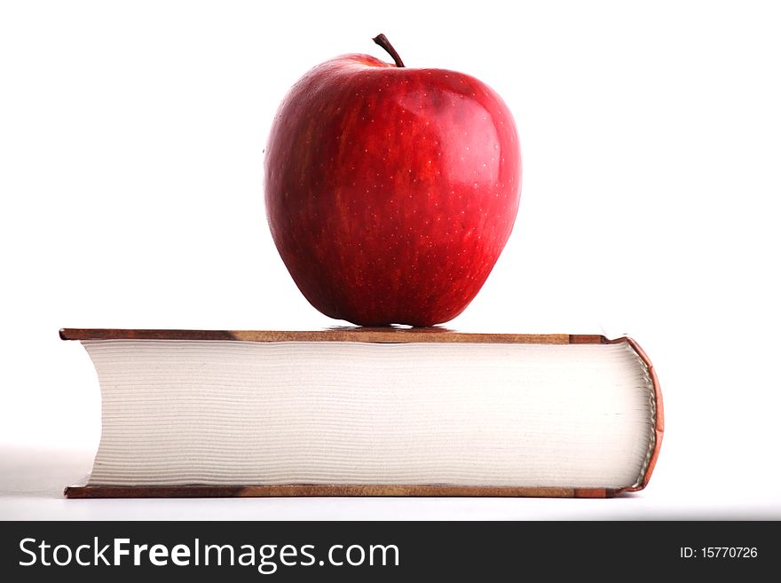 Red apple on the big book on white background