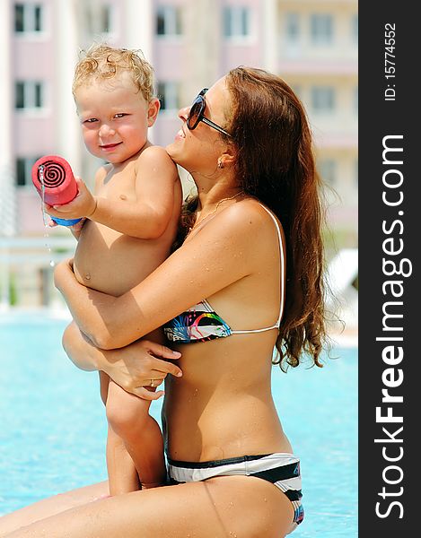 Portrait of smiling beautiful woman and her little cute sun in pool outdoor. Portrait of smiling beautiful woman and her little cute sun in pool outdoor