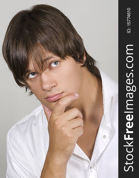 Closeup of a handsome young man thinking against white background