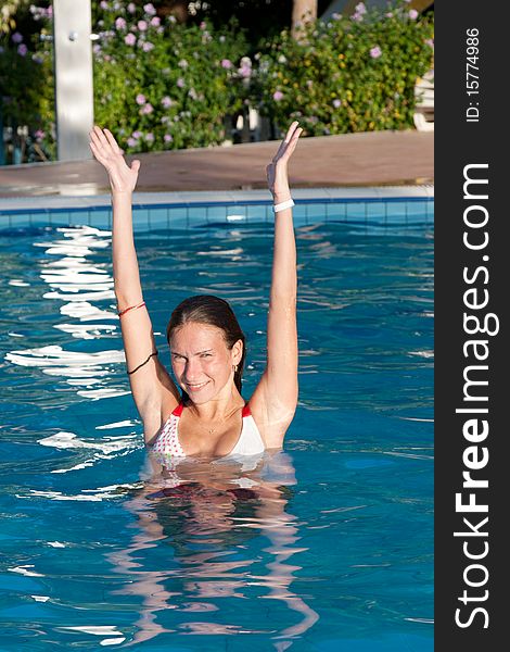 Girl in swimming pool, hands up