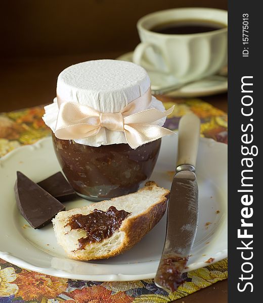 Croissant with chocolate cream and jar of chocolate cream on plate