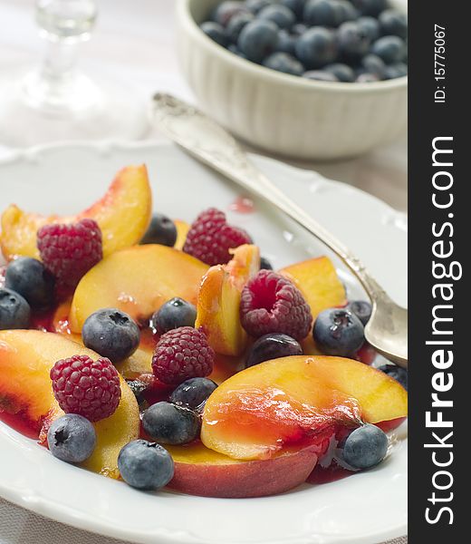 Mix of different fruits and berries salad on white plate. Mix of different fruits and berries salad on white plate