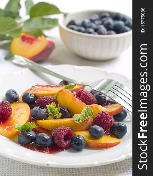 Mix of different fruits and berries salad on white plate. Mix of different fruits and berries salad on white plate