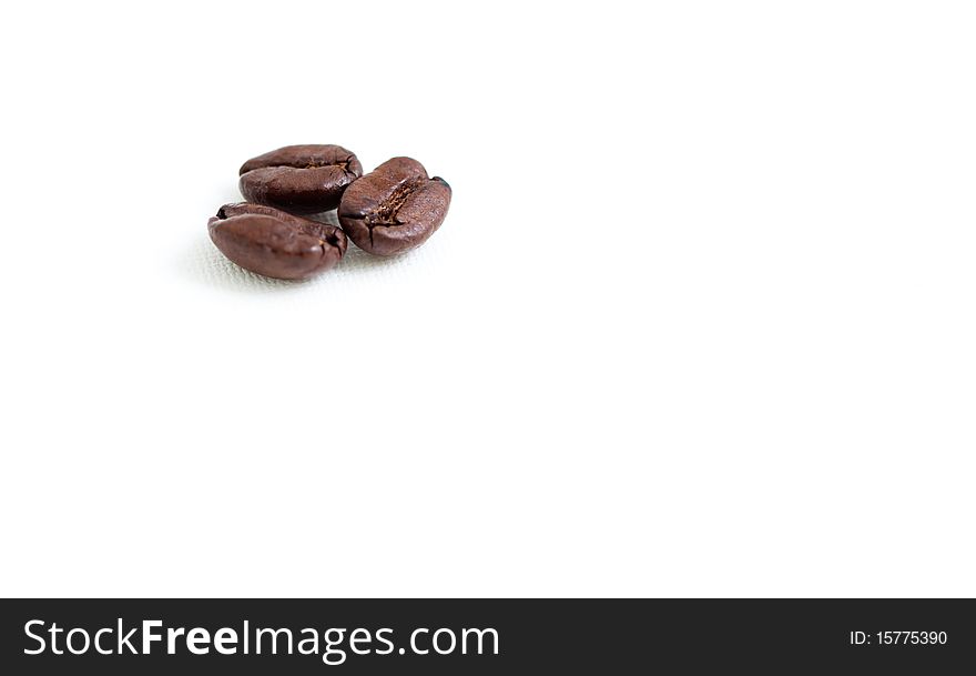 A macro shot of three coffee beans on a white background. A macro shot of three coffee beans on a white background.