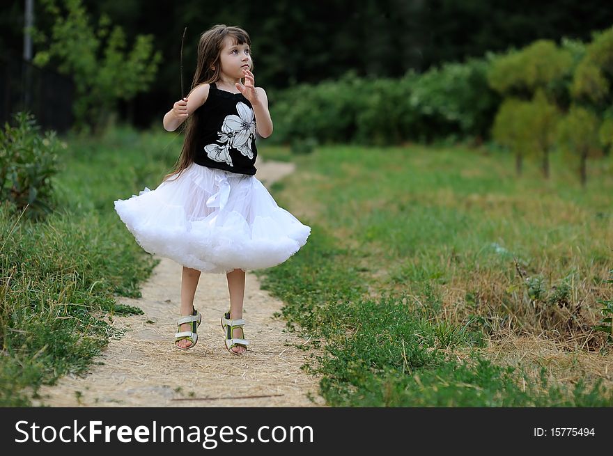 Adorable toddler girl in white tutu skirt with very long dark  fluttering hair jump  on country road. Adorable toddler girl in white tutu skirt with very long dark  fluttering hair jump  on country road