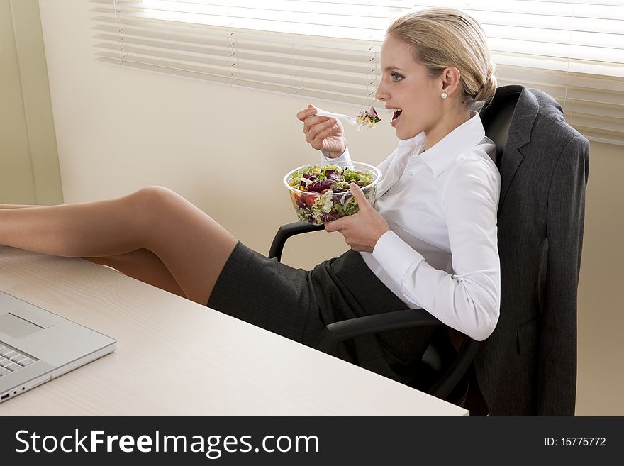 Young businesswoman eating salad in her office. Young businesswoman eating salad in her office