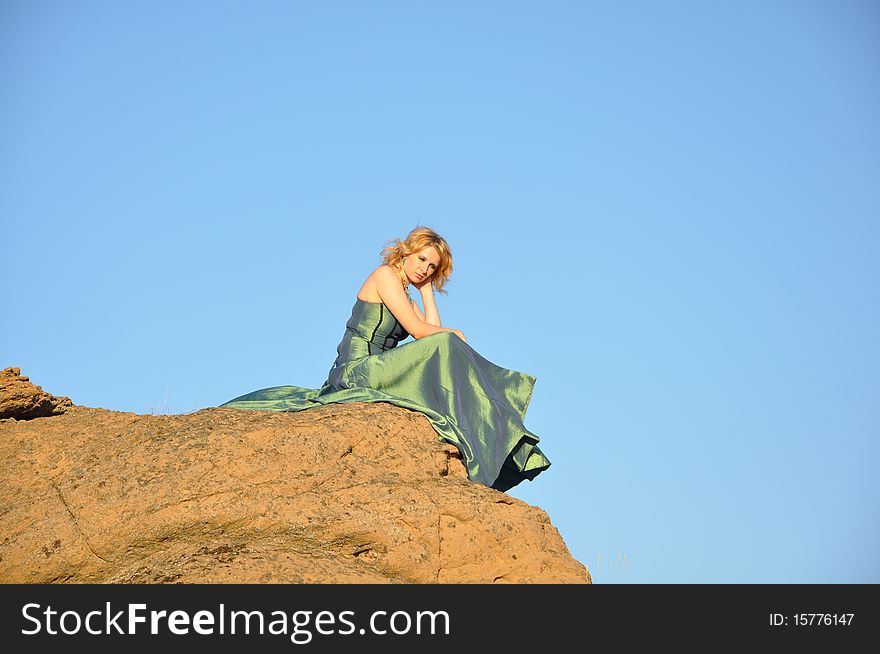 Attractive woman siting on a brink of rock and feeling sad. Attractive woman siting on a brink of rock and feeling sad