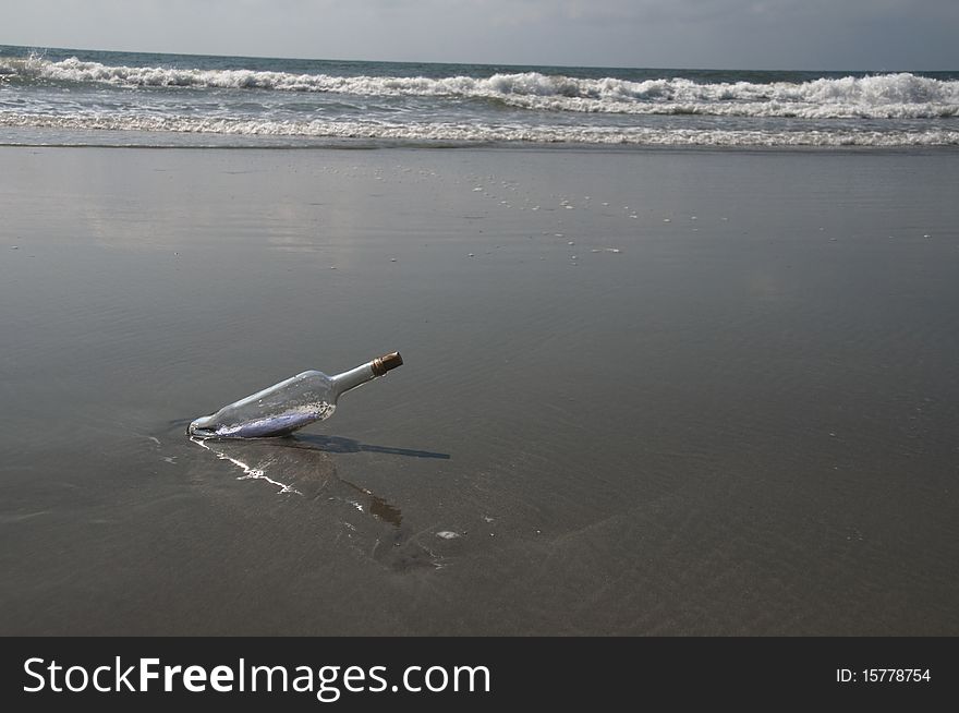 A bottle sits on a beach with a message inside. A bottle sits on a beach with a message inside.