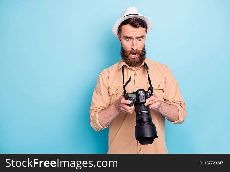 Portrait of impressed person holding camera screaming unbelievable wearing brown t-shirt  over blue background