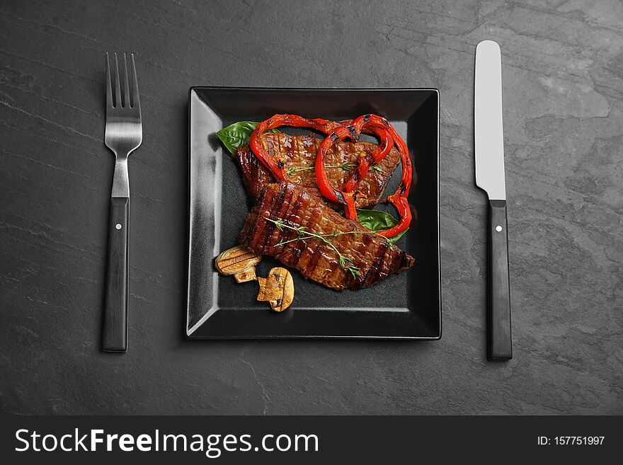 Flat lay composition with grilled meat on black table