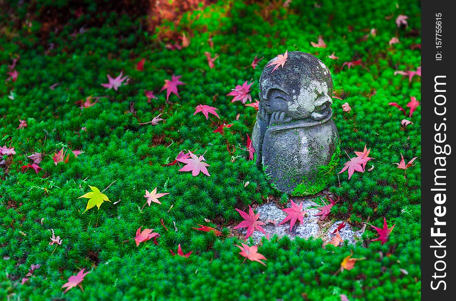 Red Maple leaf on head of Jizo sculpture doll in Japanese Garden, Enkoji Temple, Kyoto, Japan