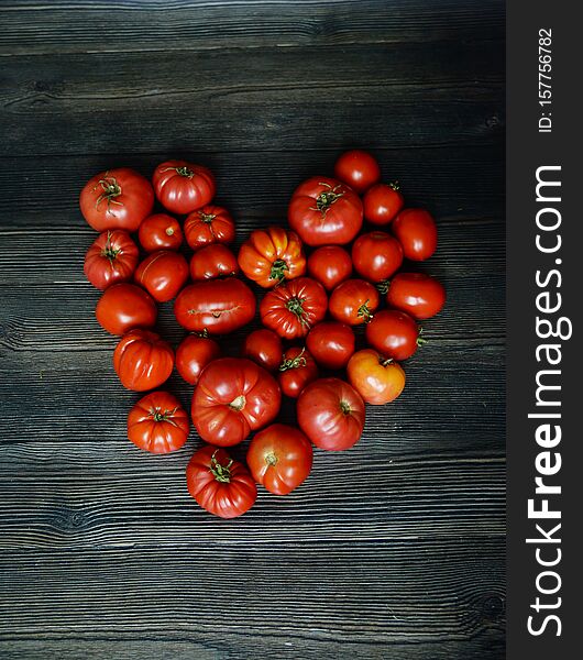 Tomatoes on the old table. Red Food background. Tomatoes heart. Top view of fresh vegetable on a dark wooden background