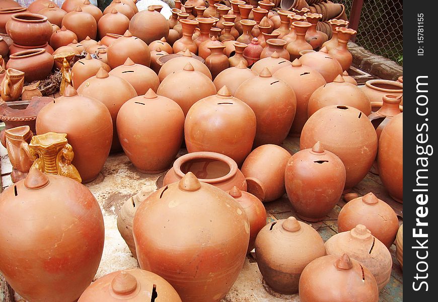 A group of different shaped earthen pots, and piggy banks in various shades of orange, made out of clay