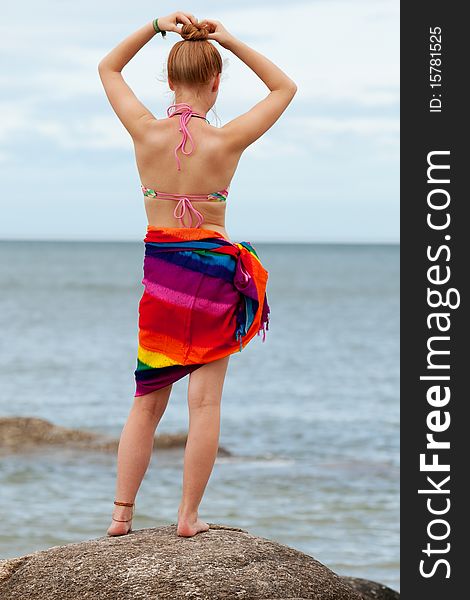 Woman on the beach, in bikini and bath towel with look to the sea