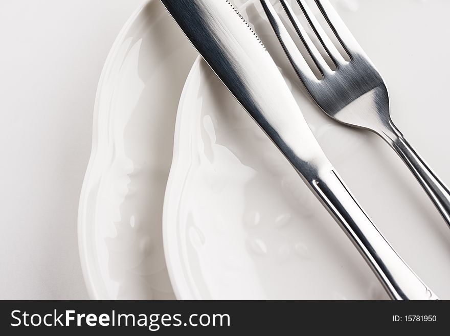 Close up of white dinner plates with silver knife and fork. Close up of white dinner plates with silver knife and fork.