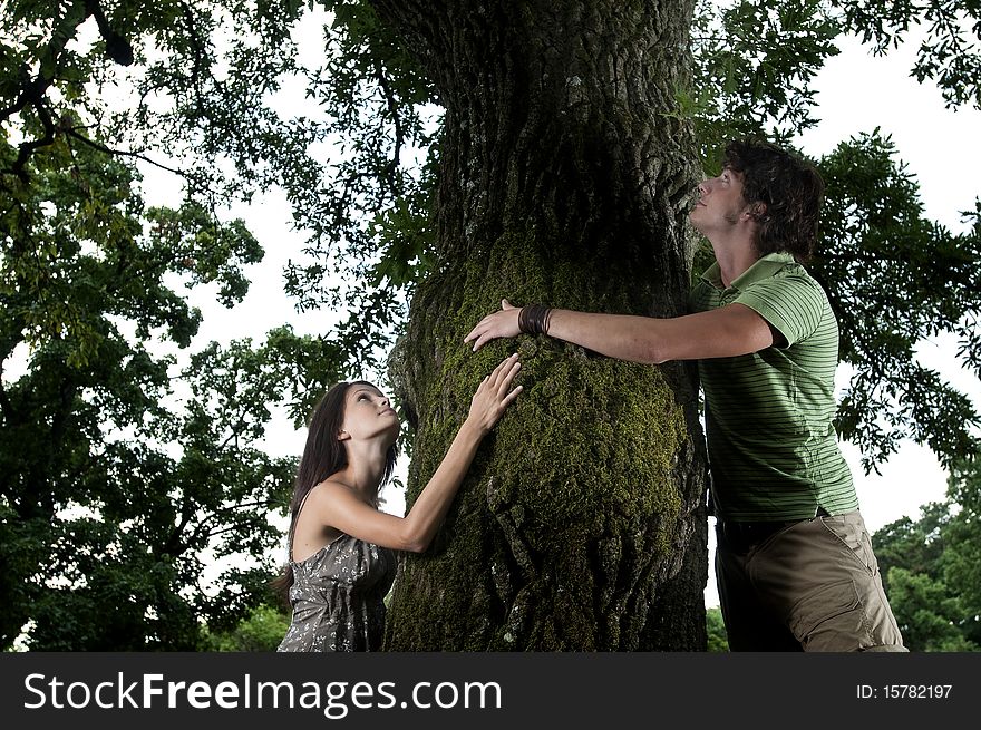 Two nature loving teenagers embracing a tree in a wood, taken in Lipica, Slovenia. Concept: care of nature. Two nature loving teenagers embracing a tree in a wood, taken in Lipica, Slovenia. Concept: care of nature