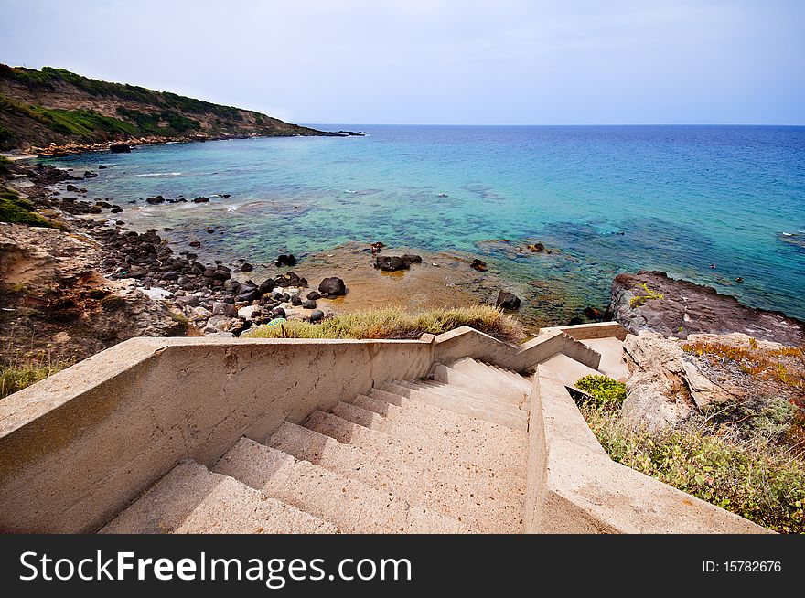 Coast of Sardinia, sea, sand and rocks with blue sky and clouds