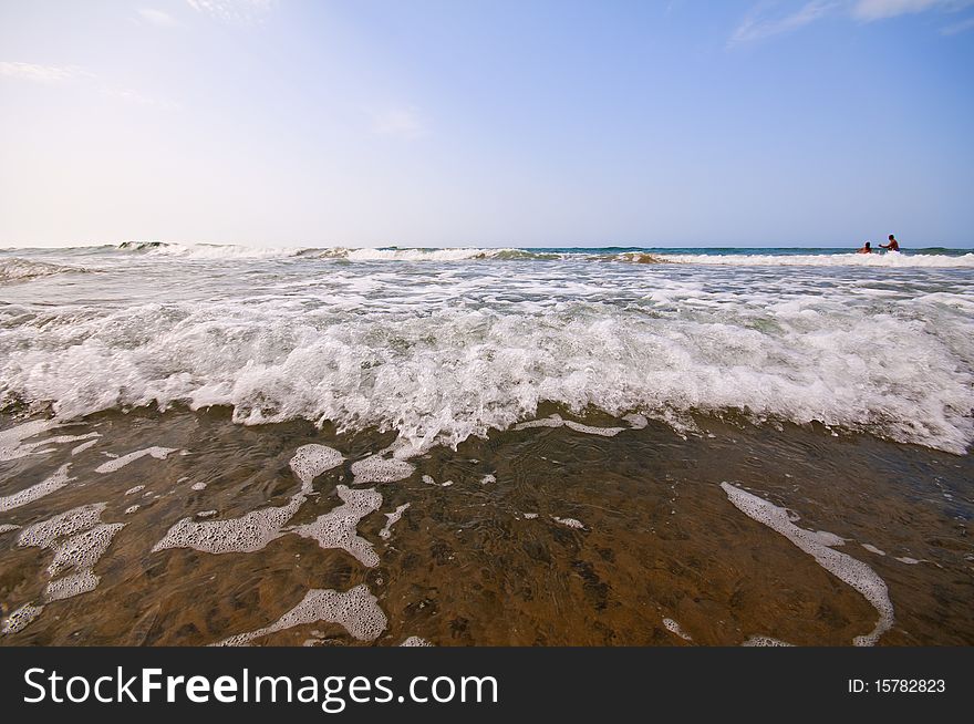 Seashore with waves and foam and blue sky
