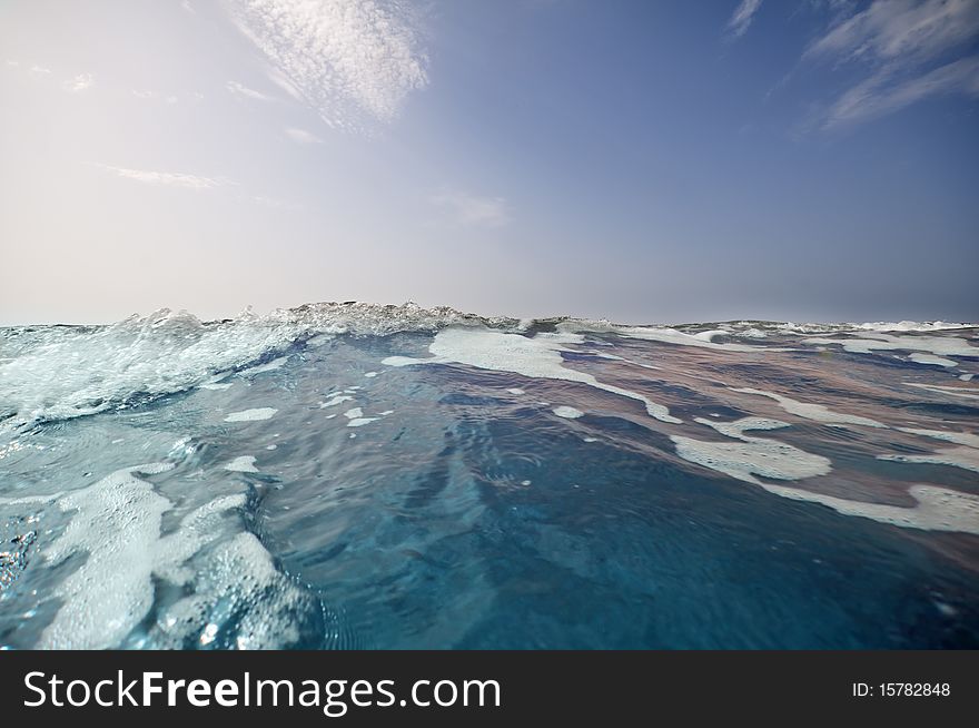 Seashore with waves and foam and blue sky